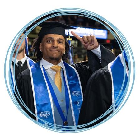 An undergraduate student in academic regalia smiles at their Commencement