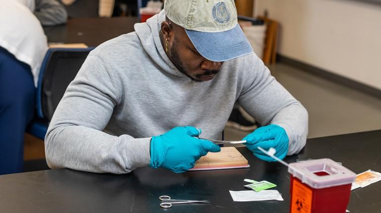 A C O M student practices suturing on a pig's foot