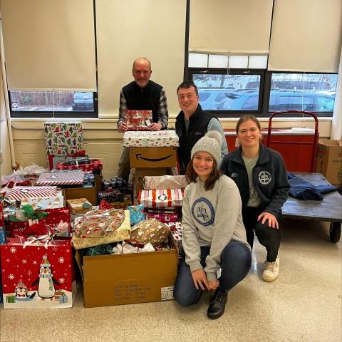 Members of UNE's Pediatrics Club and Sigma Sigma Phi pose with a variety of wrapped presents they plan to donate